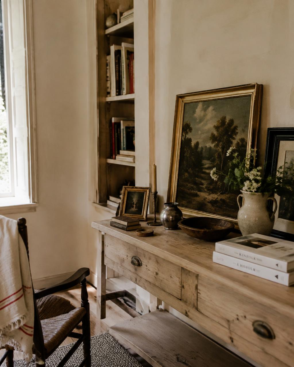 Rincón con cuadros apoyados, libros y una consola de madera