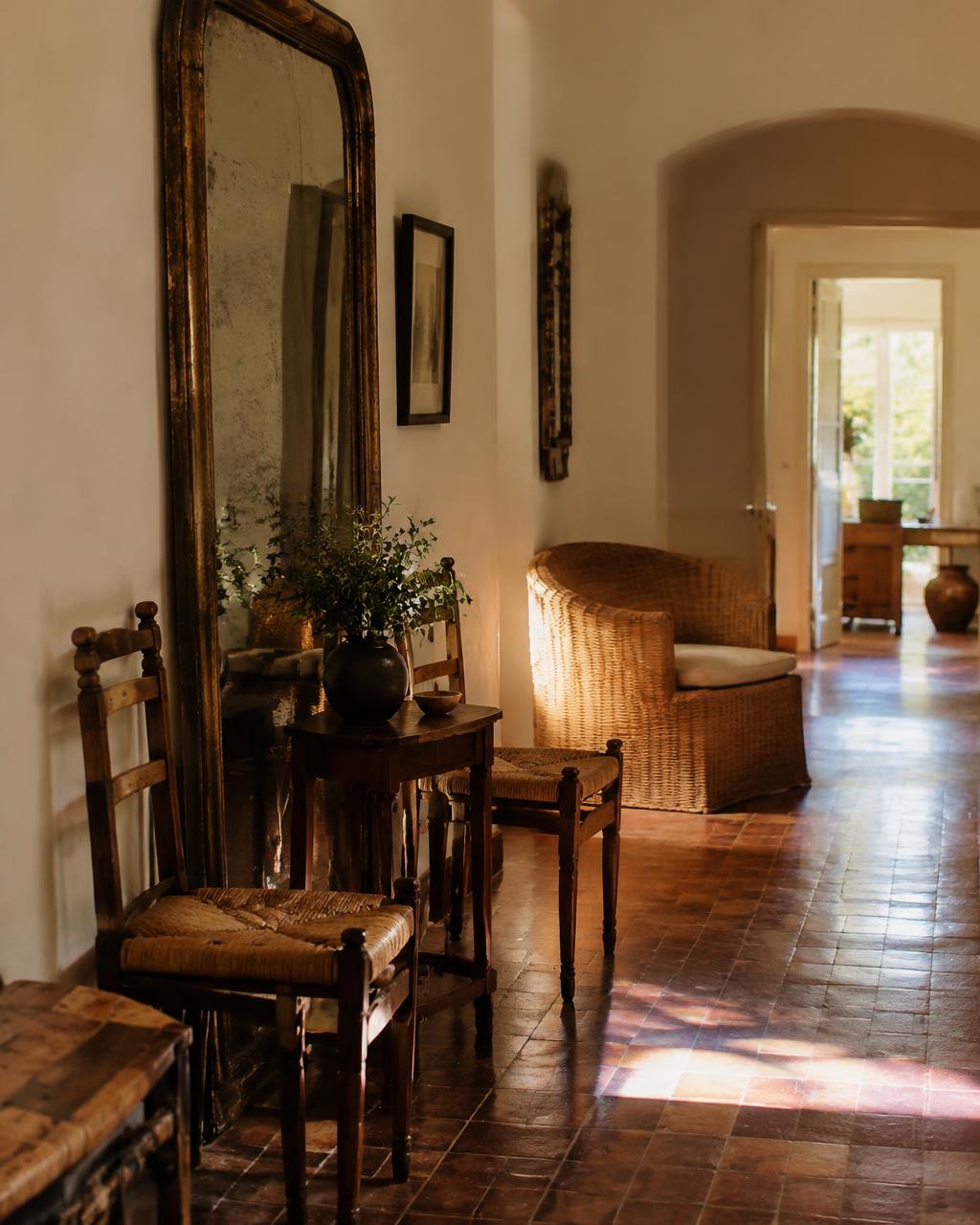 Pasillo de una casa con sillas antiguas de anea y un espejo envejecido